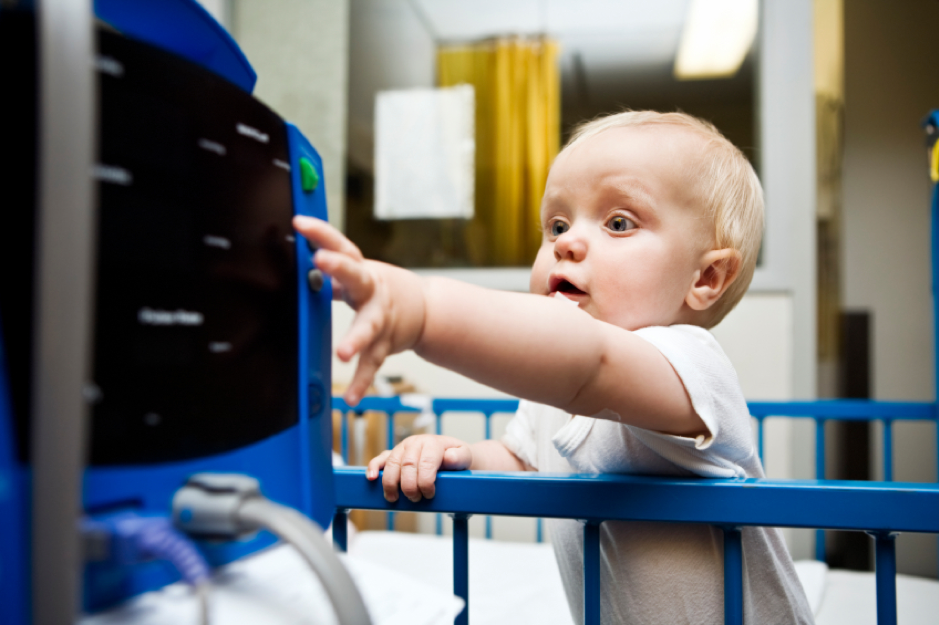 Decorative image of toddler reaching out to touch controls on medical equipment